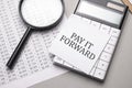 Notebook with text PAY IT FORWARD sheet of white paper for notes, calculator, magnifying glass. Business concept Royalty Free Stock Photo