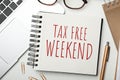 Notebook with text TAX FREE WEEKEND, laptop and pen on white table Royalty Free Stock Photo