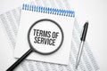 In the notebook is the text of Terms of Service, next to the black pen, magnifying glass. A business concept Royalty Free Stock Photo