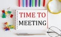 Notebook with TIME TO MEETING word with office tools on white table Royalty Free Stock Photo