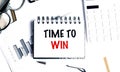 Notebook with time to win text on white office desk with glasses, pen, charts and calculator Royalty Free Stock Photo