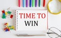 Notebook with TIME TO WIN word with office tools on white table Royalty Free Stock Photo