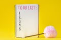 Notebook with to do list and pen with fluffy ball on yellow background Royalty Free Stock Photo