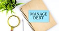 Notebook with Tools and Notes with text on blue sticker MANAGE DEBT Royalty Free Stock Photo