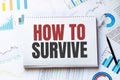 Notebook with Tools and Notes with text HOW TO SURVIVE Royalty Free Stock Photo