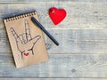Notebook of Kraft paper, which is painted with an old black marker, the symbol of ASL American Sign Language ILY and a wooden Royalty Free Stock Photo