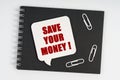 On the notebook are white paper clips and a sign with the inscription - SAVE YOUR MONEY Royalty Free Stock Photo