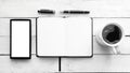 Notebook on a white wooden table next to a mobile, a pen and some coffee in a mug. Top view and empty copy space Royalty Free Stock Photo