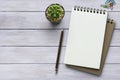 Notebook on white wooden table with a plant, paper clip and pencil. Blank notepad paper for input copy or text. Top view desk, Royalty Free Stock Photo