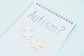 Notebook with the word autism and wooden puzzles on blue background, diagnosis of autism concept Royalty Free Stock Photo