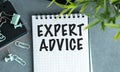 A notebook with the word Expert Advice written on it. The notebook is on a table with a pair of scissors and a pair of green. Royalty Free Stock Photo