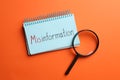Notebook with word MISINFORMATION and magnifying glass on orange background, flat lay Royalty Free Stock Photo
