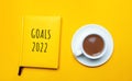 Notebook with the words Goals 2022 and a cup of coffee on a yellow background. Motivation, inspiration. Planning, plans and tasks