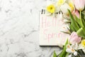 Notebook with words HELLO SPRING and flowers on white marble table, flat lay. Space for text