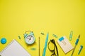 Notebook for writing pen and alarm clock with glasses on yellow background top Royalty Free Stock Photo