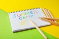 Notebook with written text SUMMER CAMP and different pencils