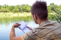 Notebook of a young man, a man close to the lake, painting landscape in Notepad. Summer Sunny day. to turn the page Royalty Free Stock Photo