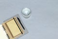 Notebooks, black pen, envelopes, glass of water on the grey background