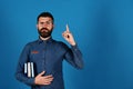 Notebooks in blue color in guys hand on blue background. Professor with confident face expression. Teacher wears glasses Royalty Free Stock Photo