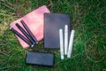notebooks of different colors, white and black felt-tip pens, and a bank, lie on the grass in a clearing Royalty Free Stock Photo