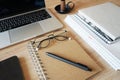 Notebooks with glasses, pen, smartphone, open laptop on wooden table Royalty Free Stock Photo