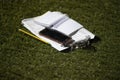 Notebooks, pencil and a smartphone on a lawn on a sunny day