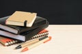 Notebooks and pens on wooden table with school black board Royalty Free Stock Photo