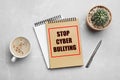Notebooks with phrase STOP CYBER BULLYING and cup of coffee on marble table, flat lay