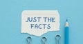 Notepad on blue office desk with text: Just The Facts. Royalty Free Stock Photo