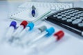 Notepad and calculator next to bottles for samples used in hospitals or medicine for blood samples in a laboratory