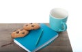 Notepad, cup, pen in turquoise color with chocolate chip cookies. wooden table and white background. Great morning and start of th Royalty Free Stock Photo