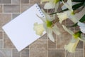 Notepad, daffodils in a vase on a brown table. Inspirational workplace.