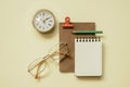 Notepad, diary, clock, eyeglasses, pencil, clip on yellow desk background. flay lay, top view, copy space