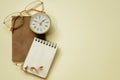 Notepad, diary, clock, eyeglasses on yellow desk background. flay lay, top view, copy space