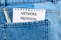 A notepad displaying the term network protocol is tucked in the back pocket of denim jeans, symbolizing essential