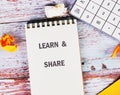 A notepad displays the words learn and share alongside crumpled paper and a calculator, emphasizing educational growth