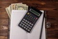 Notepad with dollars, pencil and calculator on wooden desk. Financial planning concept Royalty Free Stock Photo