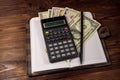 Notepad with dollars, pencil and calculator on wooden desk Royalty Free Stock Photo