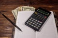 Notepad with dollars, pencil and calculator on wooden desk. Financial planning concept Royalty Free Stock Photo