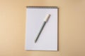 Notepad with erasable pen on beige background, top view