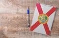 Notepad with Florida flag, pen on wooden background