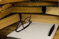 Notepad, fountain pen and glasses in front of books Royalty Free Stock Photo