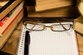 Notepad, fountain pen and glasses in front of books