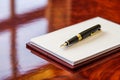 notepad with fountain pen on polished cherry desk Royalty Free Stock Photo