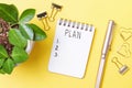 Notepad with the inscription plan on yellow background close-up top view.