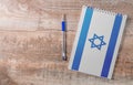 Notepad with Israel flag, pen on wooden background