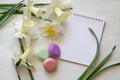 Notepad, macarons and daffodils on a white background. Inspirational workplace.