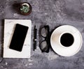 Notepad, mobile phone, pen, succulent, glasses, cup of coffee on a gray cement background. Royalty Free Stock Photo