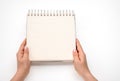 Notepad mockup. female hands holding blank spiral notepad or calendar over white table background. hands shows open notebook.