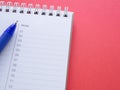 Notepad with numbers 01-12 and blue pen on a red workplace offiec background. Royalty Free Stock Photo